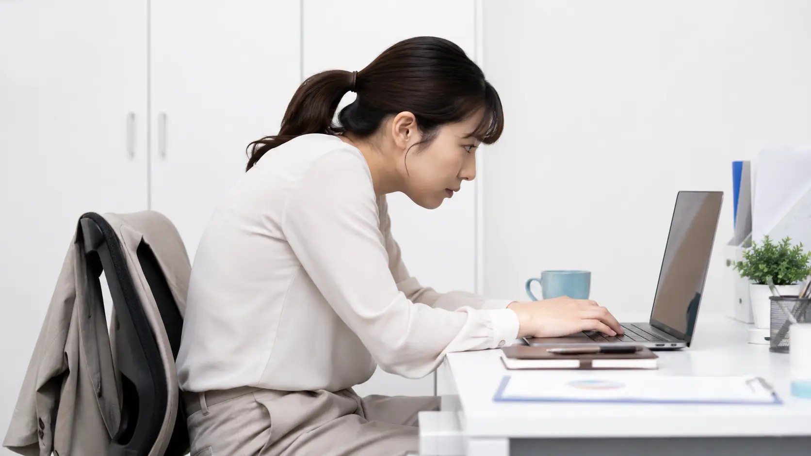 PCを操作していて、肩が前に出て首が前に落ちている(巻き肩・猫背)ビジネスパーソン